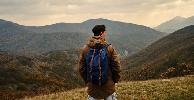 Hiker man with backpack in mountains at autumn season