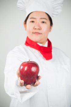 cooking and food concept - smiling female chef, holding a Red Delicious