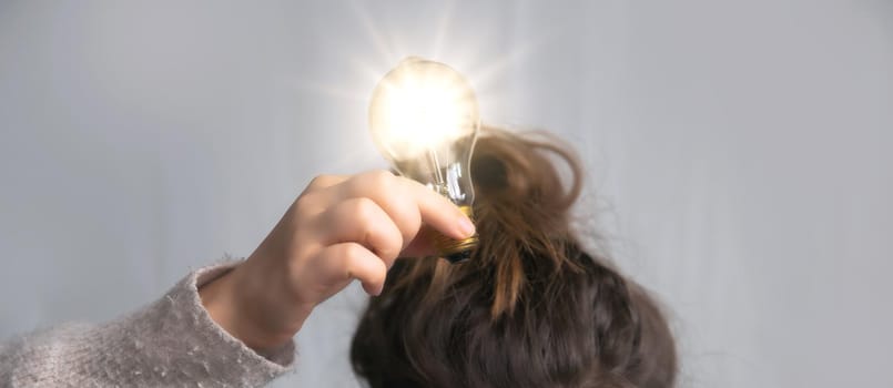 Young female holding light bulb above head in her hand,creativity,business,solution,thinking,ideas concept, copy space space for text