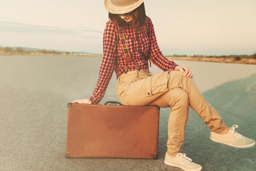 Traveler young woman sitting on suitcase. Low contrast effect