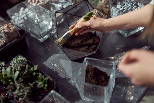 caucasian confident happy florist is working with composition made from glass stones and plants in botanic shop