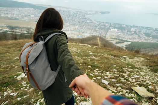 Traveler woman holding man's hand and leading him on nature outdoor. Couple in love. Focus on woman