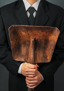 Businessman in a suit holding metal shovel, face is not visible. Concept of business creation
