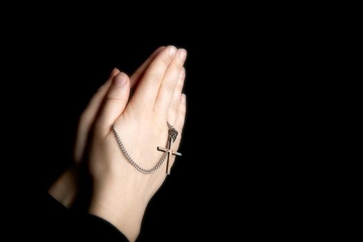 Praying hands holding a rosary, Closeup holding necklace with cross,pray for god in the dark, religious Christian symbol with copy space background