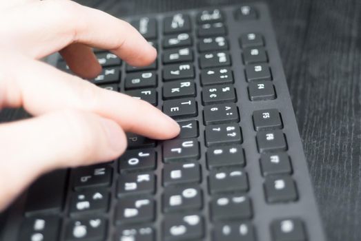 Pressing the keyboard closeup. Black keyboard on the desk