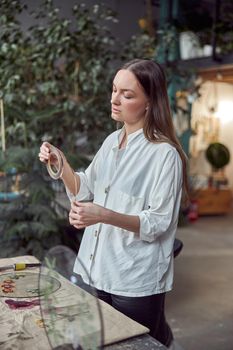 Confident female florist is working with dryed flowers in cozy flower shop