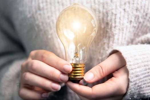 Female hand holding a shining light bulb, Great idea, innovation and inspiration, business concept background modern retro design