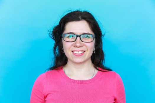 Cheerful beautiful young student woman with glasses over blue background