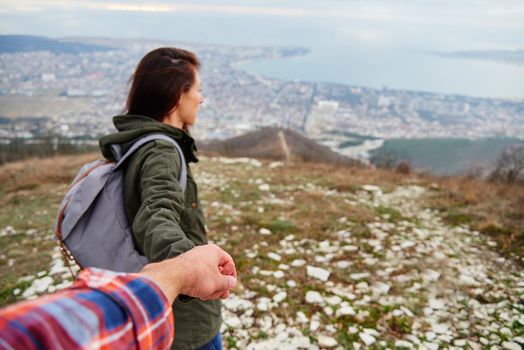 Young traveler woman holding man's hand and leading him on nature outdoor. Couple in love. Focus on hands