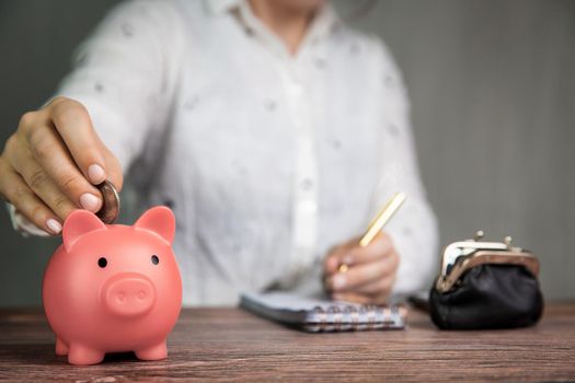 Female business woman doing administration, counting and saving money with pink piggy bank, business, savings,tax,financial concept background office table