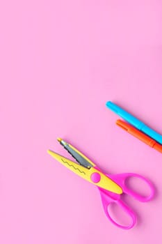 scissors, ruler and crayons on a pink vertical background. Creative, fashionable, minimalistic, school or office workspace with supplies on cyan background. Flat lay.