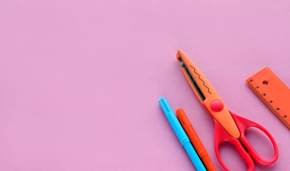 scissors, ruler and crayons on a pink background. Creative, fashionable, minimalistic, school or office workspace with supplies on cyan background. Flat lay.