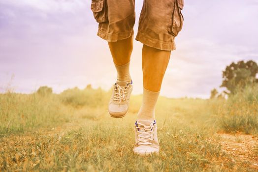 Unrecognizable man running on footpath in summer, view of legs. Image with sunlight effect. Theme of sport and healthy lifestyle