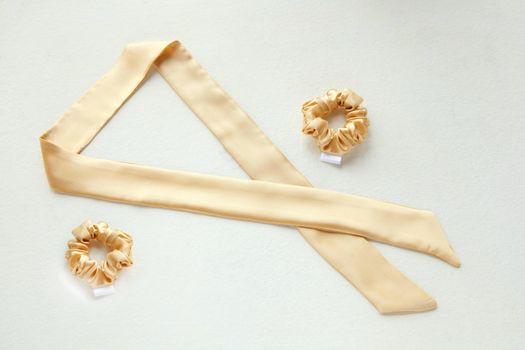golden silk scrunchy flat lay on white. Hairdressing tools and accessories. luxury ladyes Hair Scrunchie, Elastic Hair Band, Bobble Sport Scrunchie Hairband. hair scarf fixed on the scrunchie