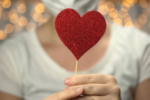Young Female holding sparkling red heart wearing white protective medical mask for coronavirus, Covid-19 and Valentine's day, Healht concept romantic love