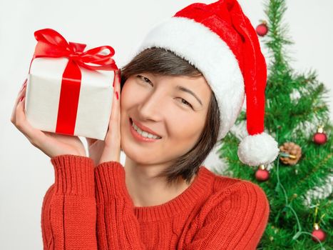 Happy woman in santa hat is holding gift box