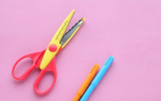 scissors, ruler and crayons on a pink background. Creative, fashionable, minimalistic, school or office workspace with supplies on cyan background. Flat lay.