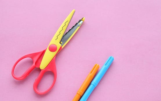 scissors, ruler and crayons on a pink background. Creative, fashionable, minimalistic, school or office workspace with supplies on cyan background. Flat lay.