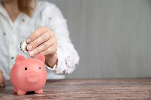 Piggy bank saving currency, person putting coin in for saving money, business, financial, savings and tax concept with copy space space for text