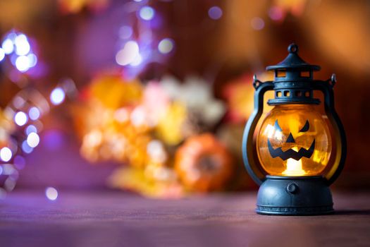 Jack o lanterns Halloween pumpkin face in lantern autumn colored background with bokeh lights and autumn leafs copy space