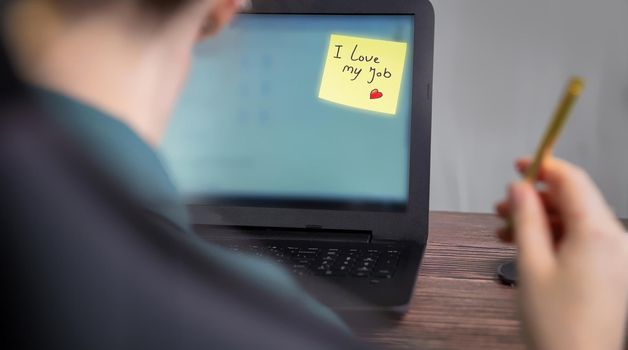 Business woman sitting in her home office with laptop and sticky note with the text I Love my job, business,work, passion,ambition,motivation concept copy space modern background