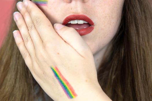 Portrait of a young woman with rainbow Flag on cheek and body, the LGBT community on a colorful pink background freedom, LGBTQ concept beauty