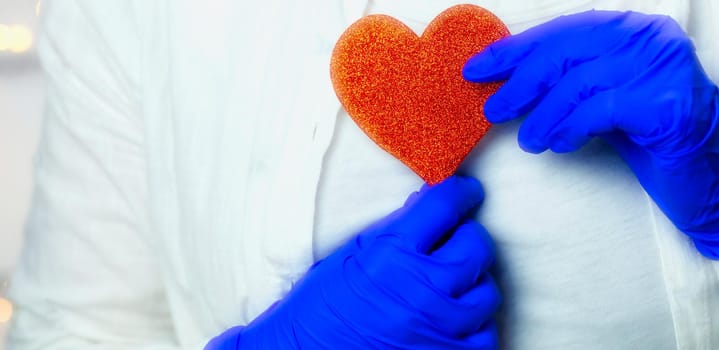 Healthcare worker holding red heart with blue medical gloves for epidemic coronavirus or other virus, health and love Valentine concept. human beauty