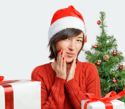 Young woman in santa hat surprised on fir-tree background