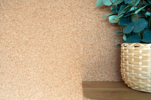 Cork background texture with green plant in a decorative basket in modern interior on wood shelf, natural brown simple colors with copy space, stylish decoration nature