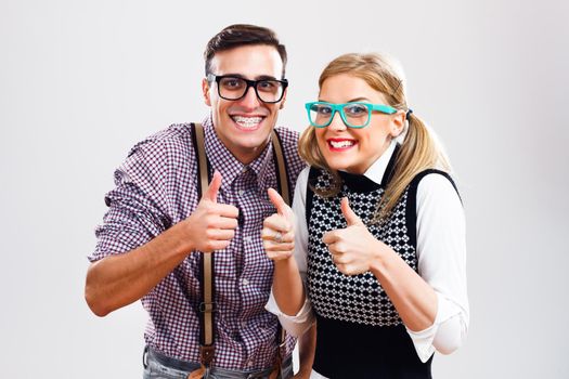 Portrait of happy nerdy couple showing thumbs up