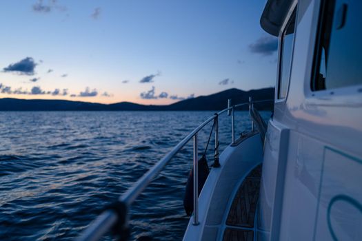 Deck of white yacht sailing in open sea at sunset, close up