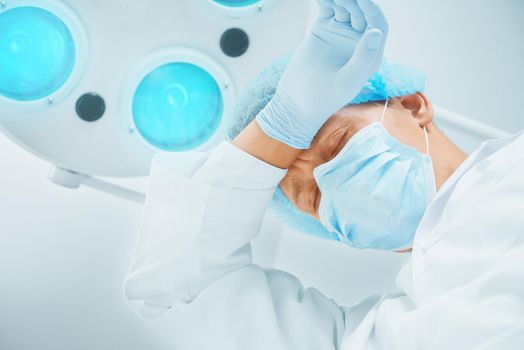 Portrait of tired young man surgeon doctor in protective uniform after operation
