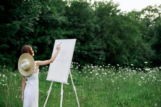 Woman in white dress paints a picture outdoors hobby creative. High quality photo