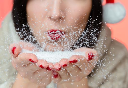 Unrecognizable woman is blowing on snow