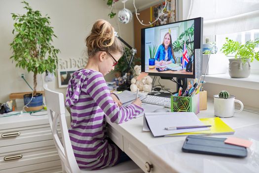 Learning English concept. Girl child at home studying language at home, online lesson, distance learning, e-education. Little student girl talking to teacher writing and reading