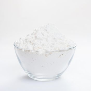 White flour in a transparent bowl, side view