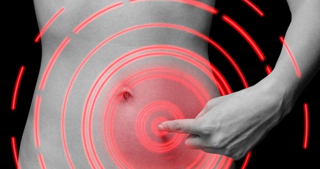 Unrecognizable woman points to painful area on abdomen, black and white image