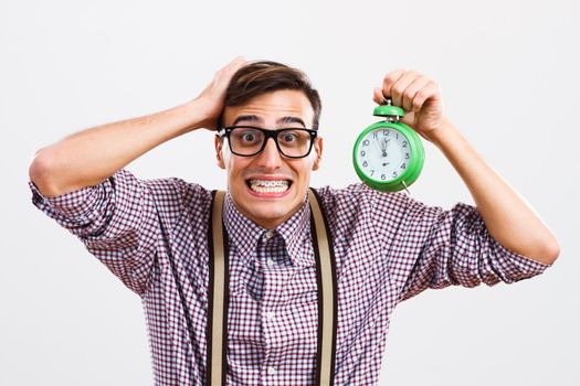 Portrait of nerdy man in panic holding clock.