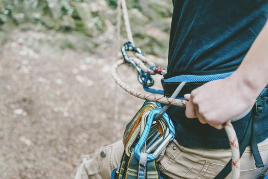 Unrecognizable female climber wearing in safety harness belaying with figure eight.