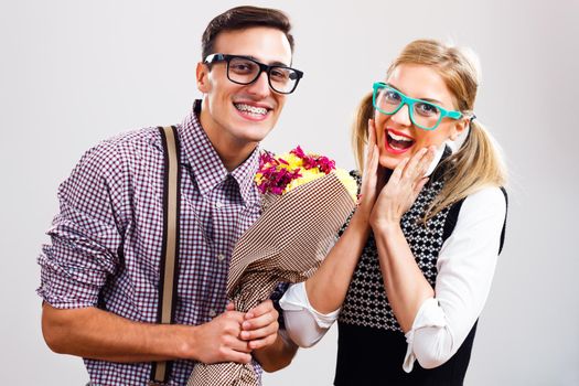 Nerdy man is giving flowers to his nerdy lady.