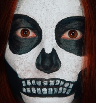 Portrait of scary skull woman with Halloween makeup and red hair