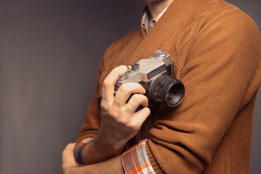 Man in sweater is holding photo camera, space for text
