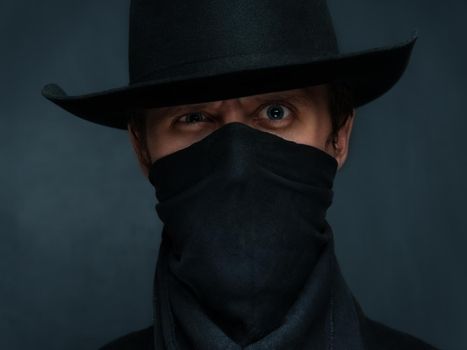 Man cowboy is surprised with a scarf on his face and in a black hat
