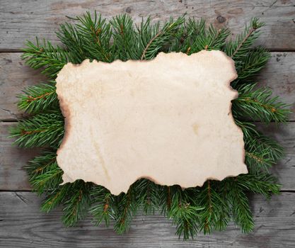 Old paper on the branches of a Christmas tree on a wooden table, top view, copyspace