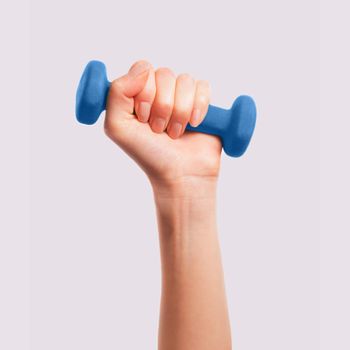 Female hand holds a dumbbell on a gray background