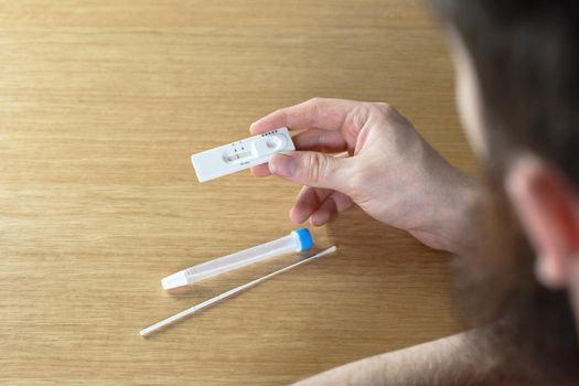 Young man holding a negative covid-19 self test at home, self test kit for Coronavirus top view with copy space close up