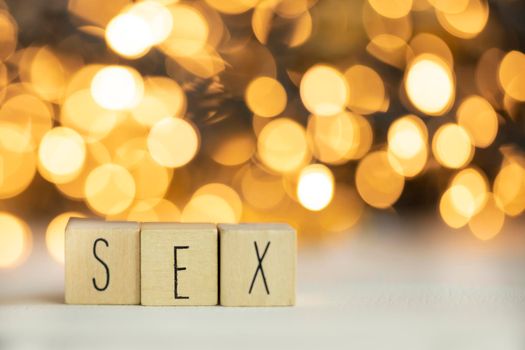 Three wooden cubes with letters SEX on them with colorful gold shiny bokeh background. space for text