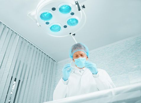 Young man surgeon takes off his protective glasses after operation