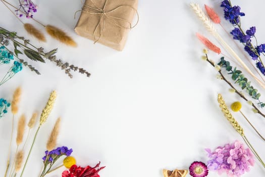 Fresh colorful dried spring flowers and brown craft paper gift box, top view with copy space isolated on white background, bright colors,flat lay,modern design, Mothers Day, Birthday,Valentines Day cheerful