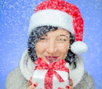 Beautiful young woman is holding a gift box in snowy weather